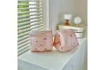 Two pink inflatable arm floats with cherry design on a white surface near a window with blinds.